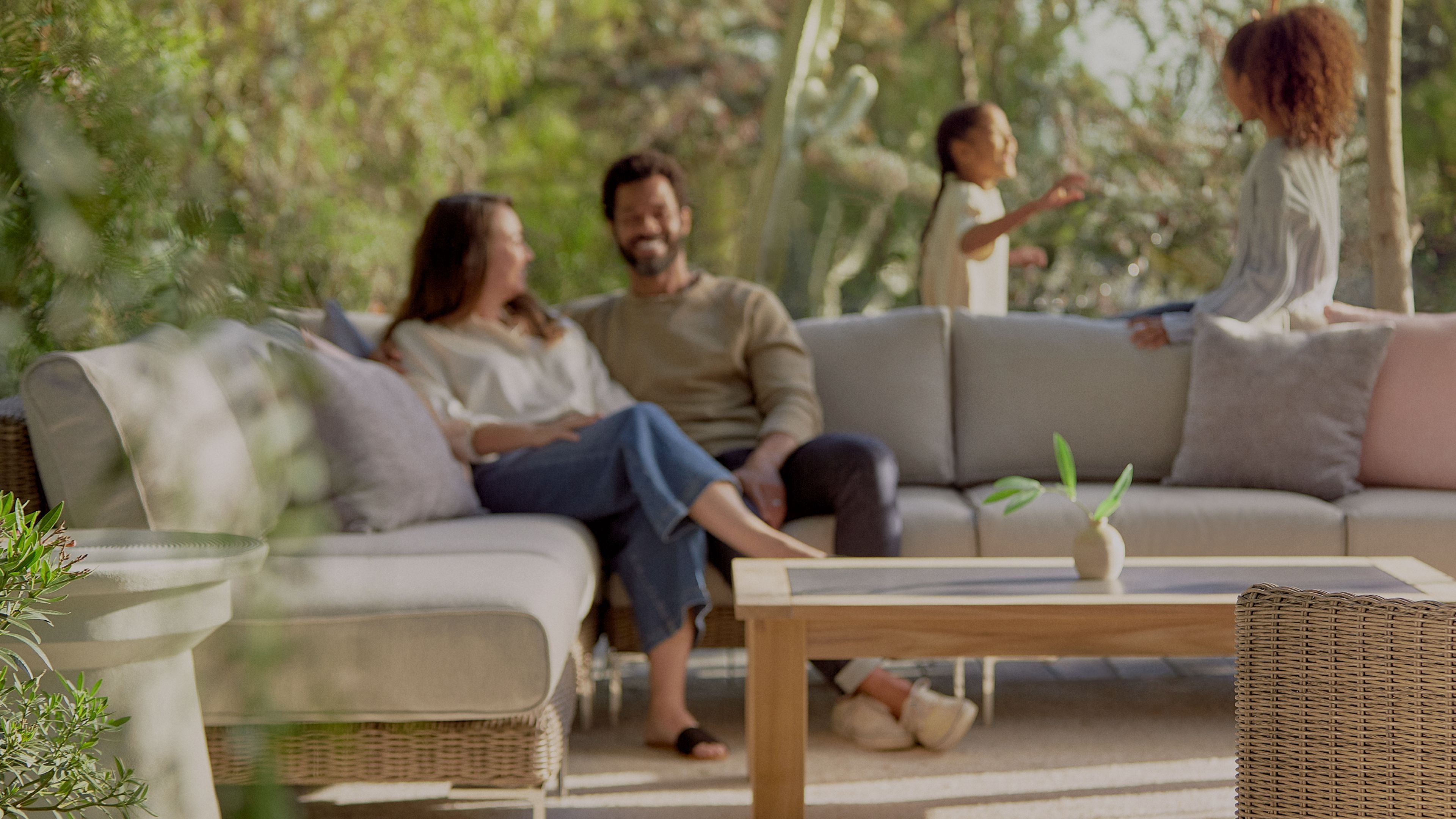 A family relaxing together on modern outdoor seating in a natural garden setting