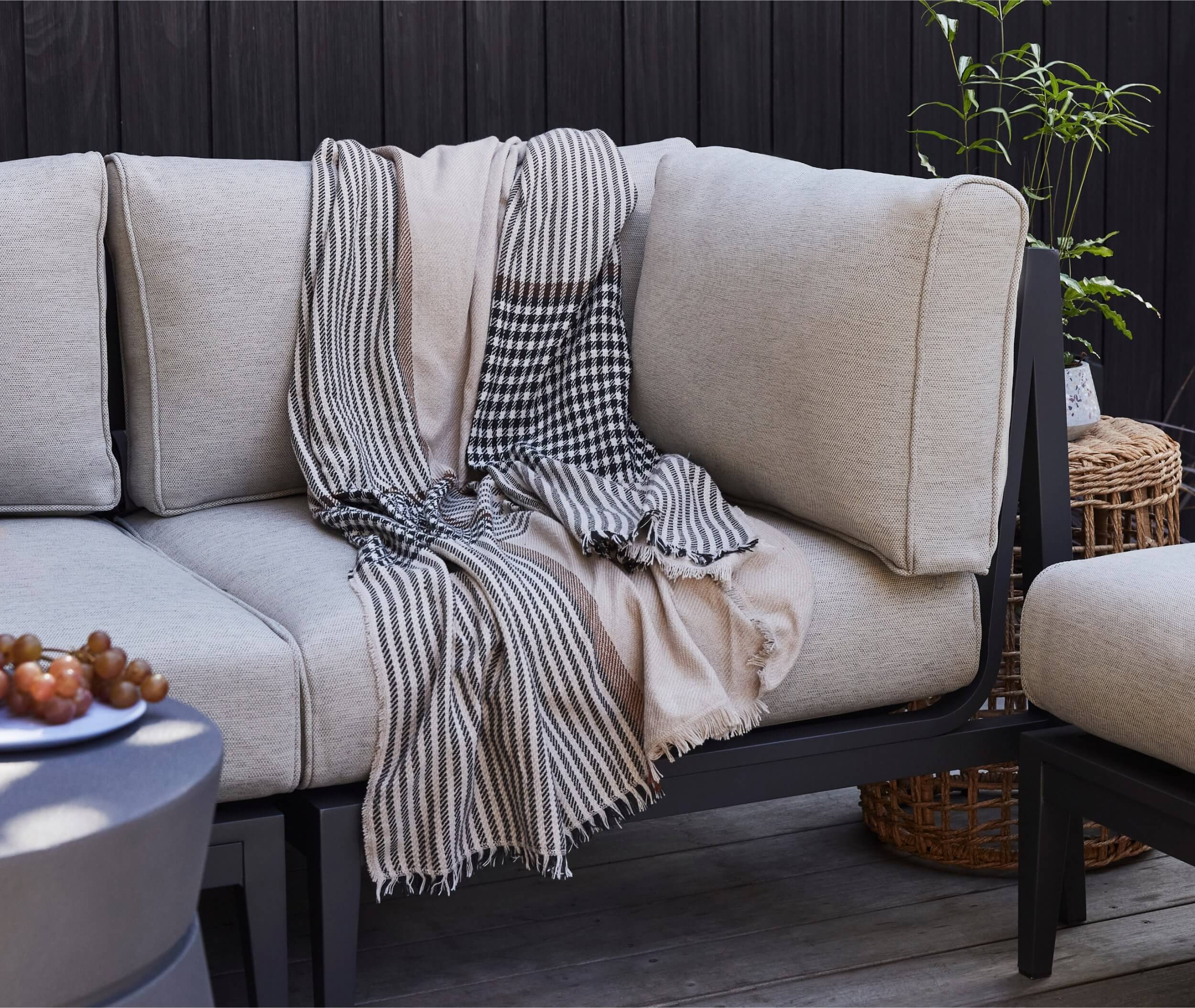 Outdoor sofa with a bug repellant blanket draped over the seat