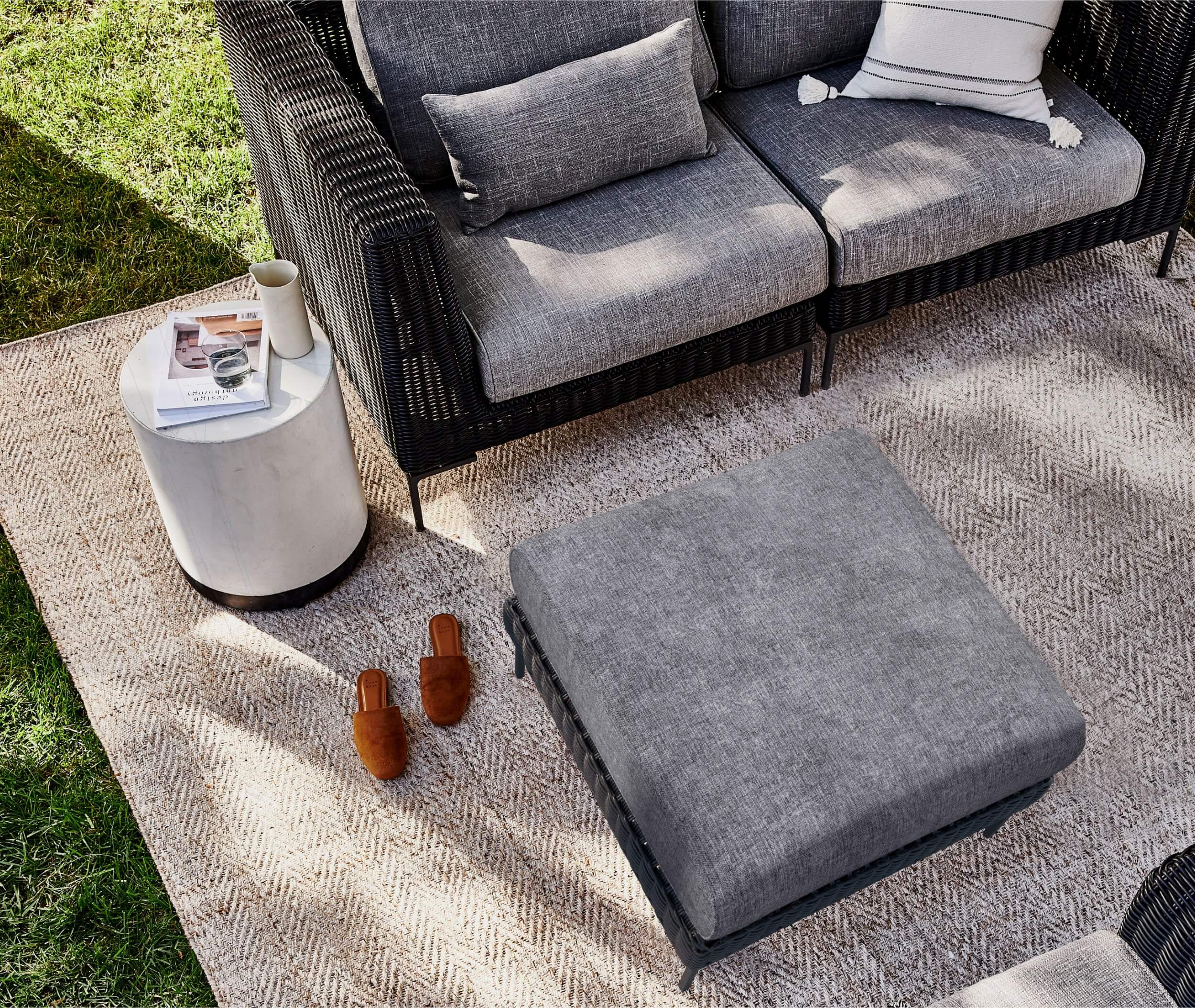 Outdoor lounge chair with matching ottoman on an outdoor rug
