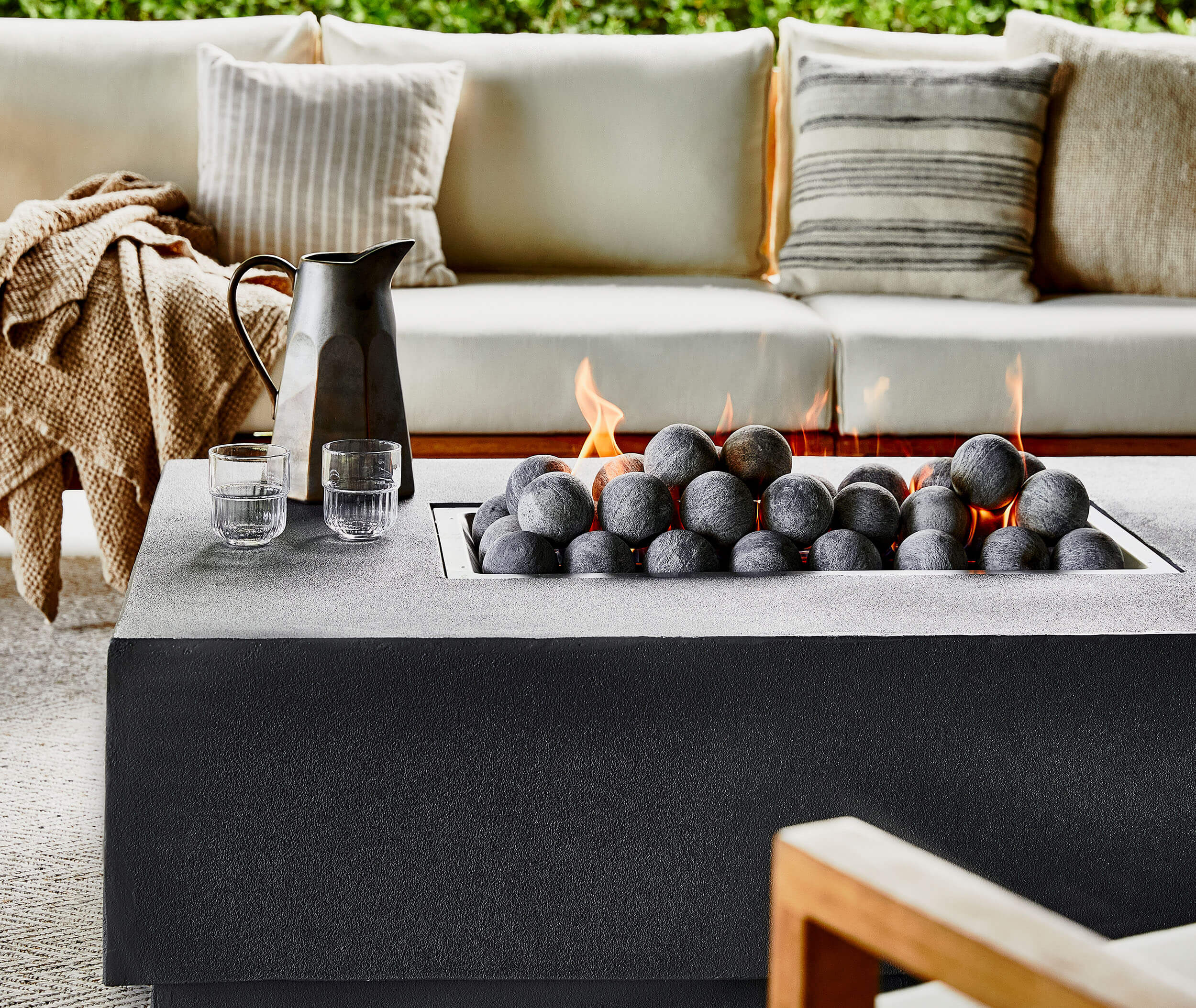 Outdoor fire pit table with flames surrounded by patio seating