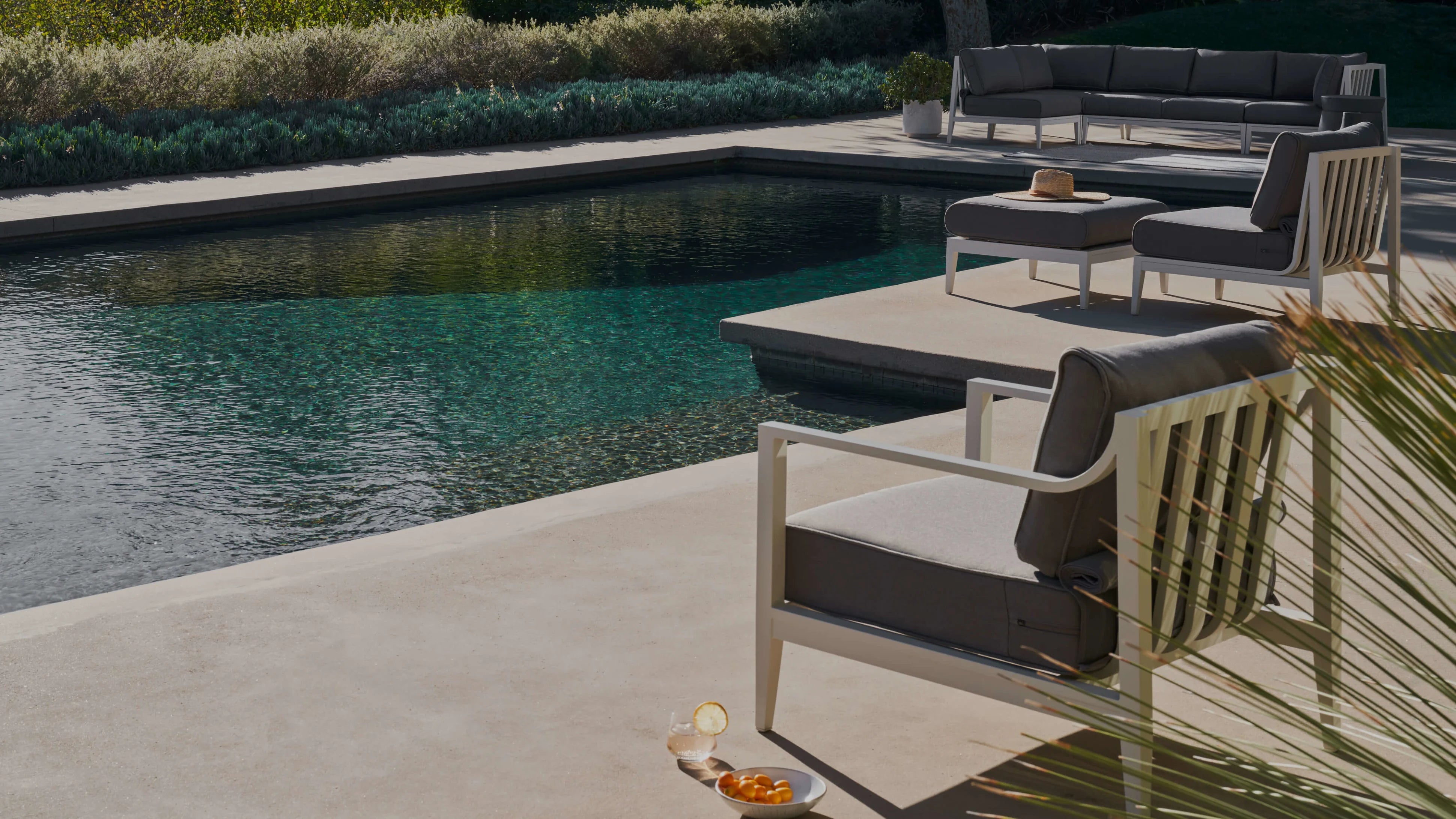 Aluminum outdoor sofa with dark cushions arranged beside a pool on a modern patio
