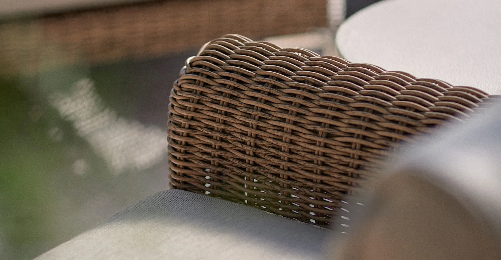 Close-up of a woven wicker chair back with gray seat cushion, showing the textured weave
