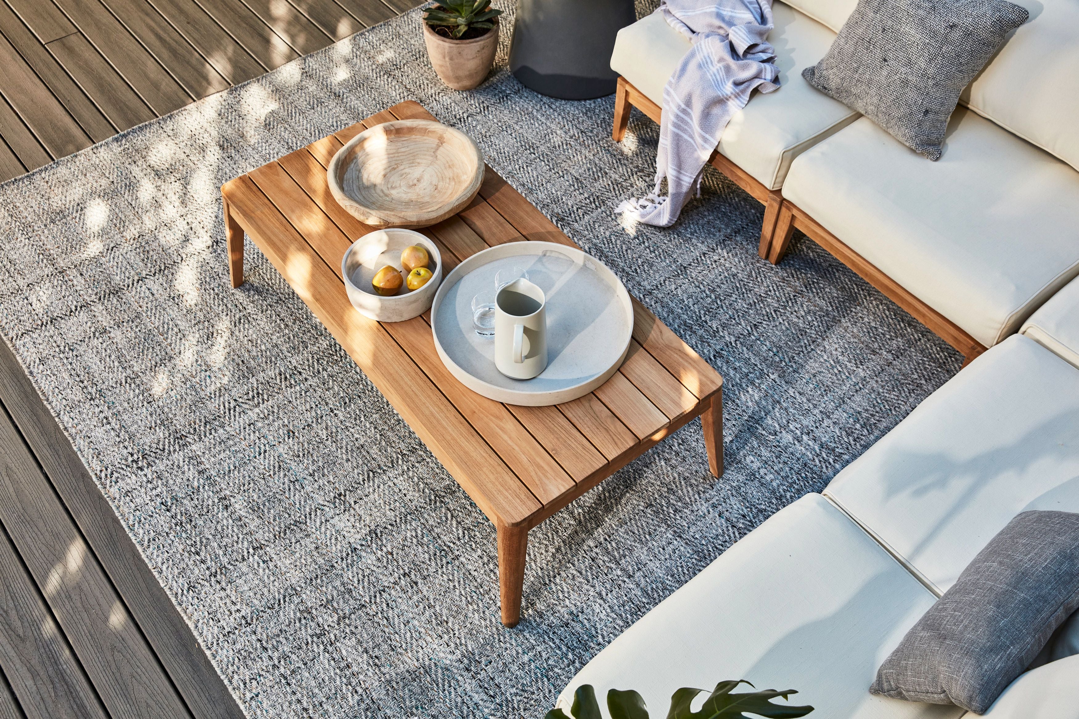 Tapered leg outdoor coffee table with sustainable teak shown with Outer's durable outdoor rug.