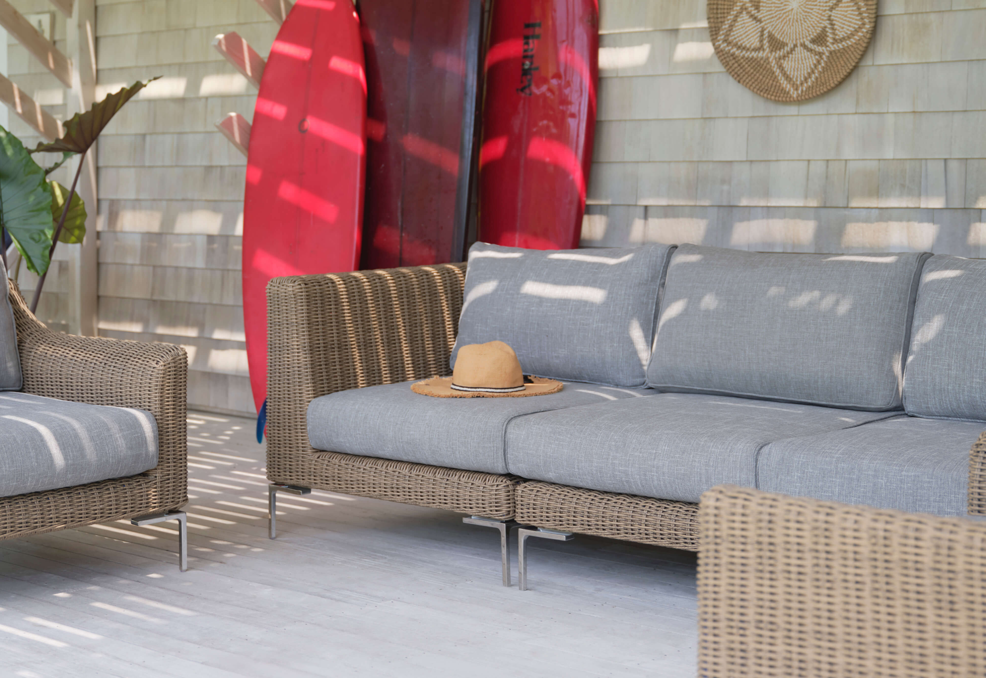 The brown all-weather wicker outdoor 3-piece sofa with pacific fog gray cushions and matching armchairs. 