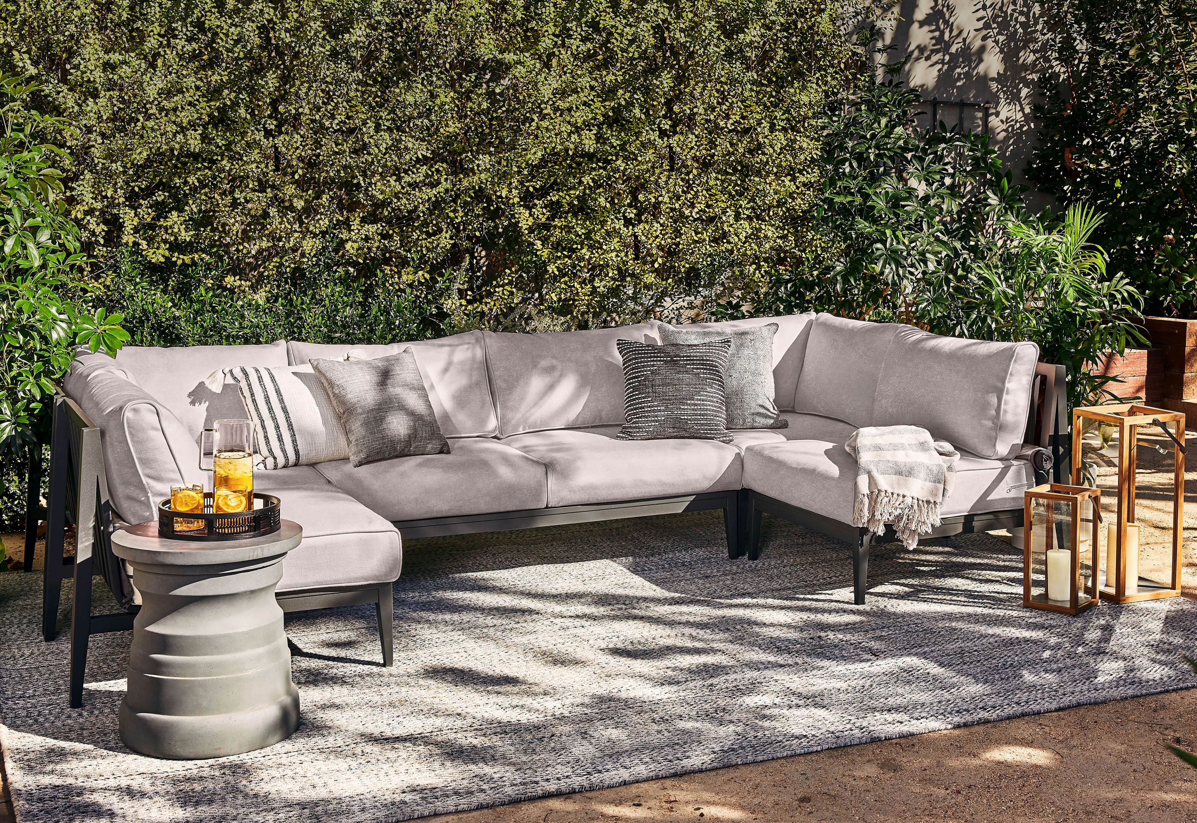 Eco-Friendly Outdoor Rug in Pebble Gray shown in a backyard with Outer's aluminum sectional and side table.