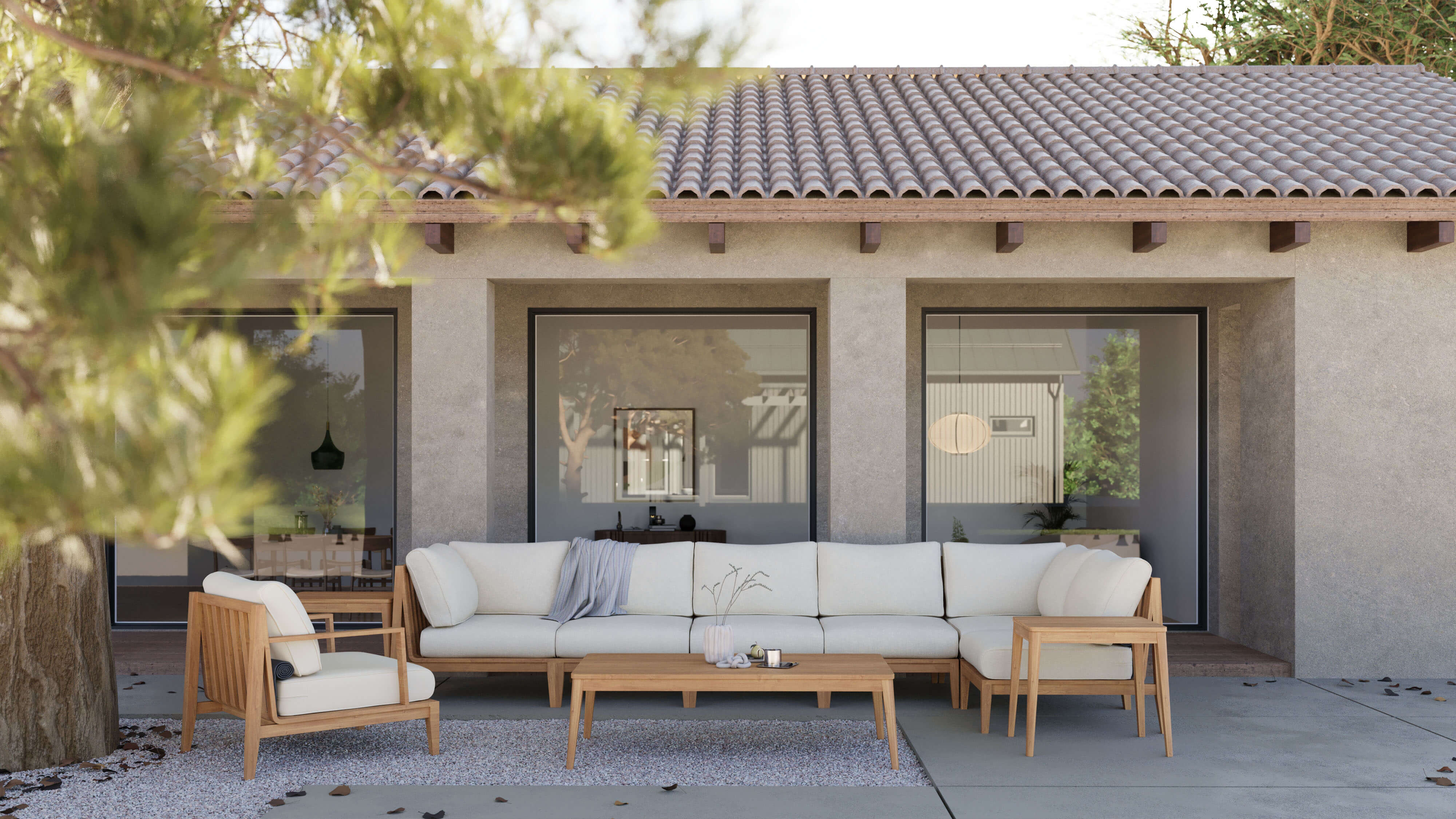 Outdoor teak loveseat sofa with cream cushions, accompanied by matching teak side and coffee tables, set on a patio with greenery in the background.-teak outdoor sofa-outer