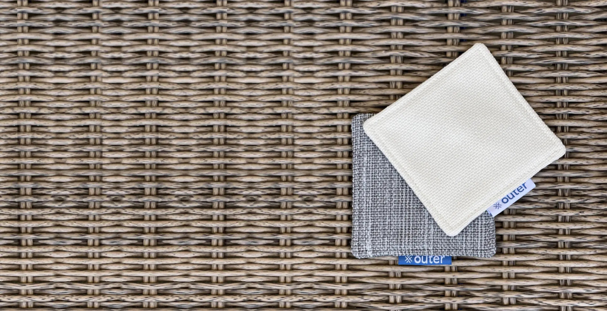 Stacked fabric swatches in neutral tones placed on a woven surface
