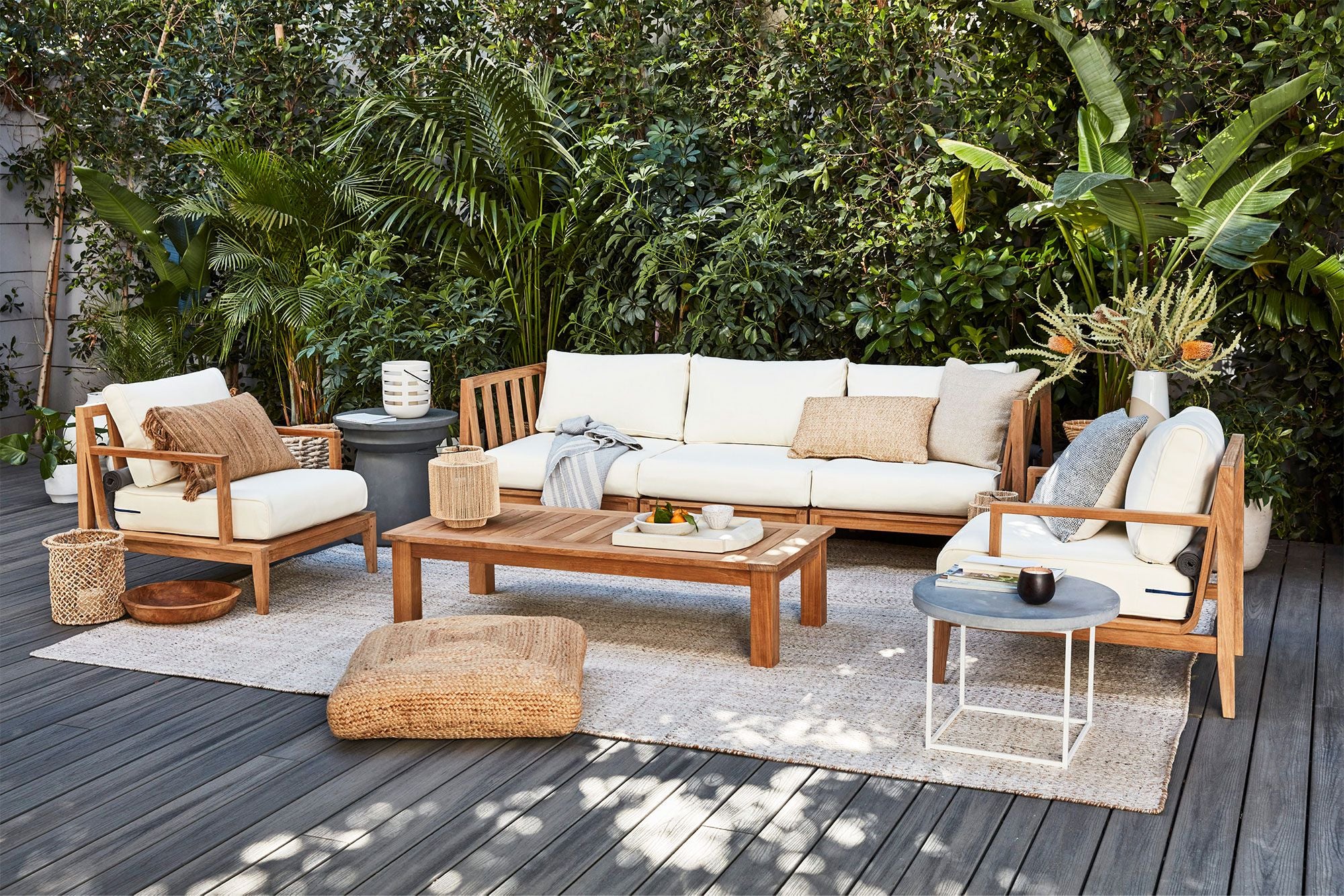 Teak outdoor loveseat sofa with white cushions, featuring sturdy wooden frame and armrests, set on a wooden deck.-teak outdoor sofa-outer