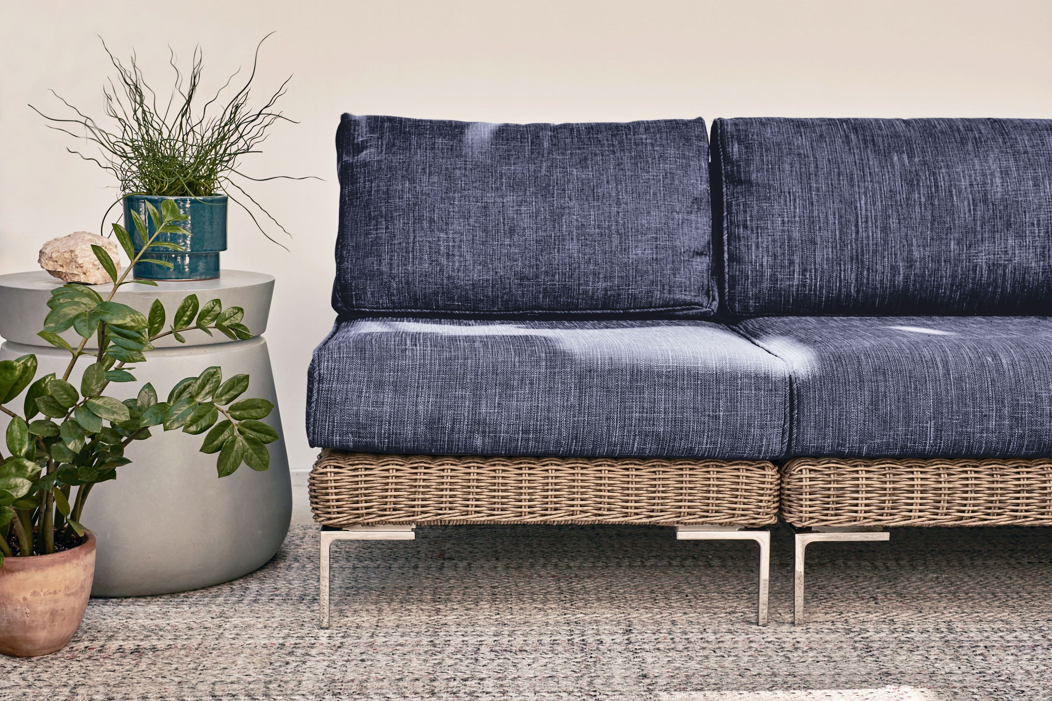 Two modular brown wicker armless chairs in navy joined together to form an armless loveseat shown on top of our sand dune beige outdoor rug. 